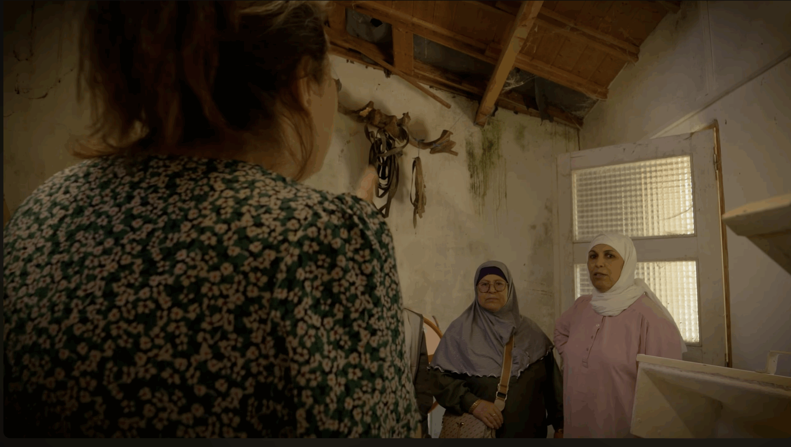 Photo 2 femmes voilées de face et une femme de dos dans un intérieur d'une maison rurale